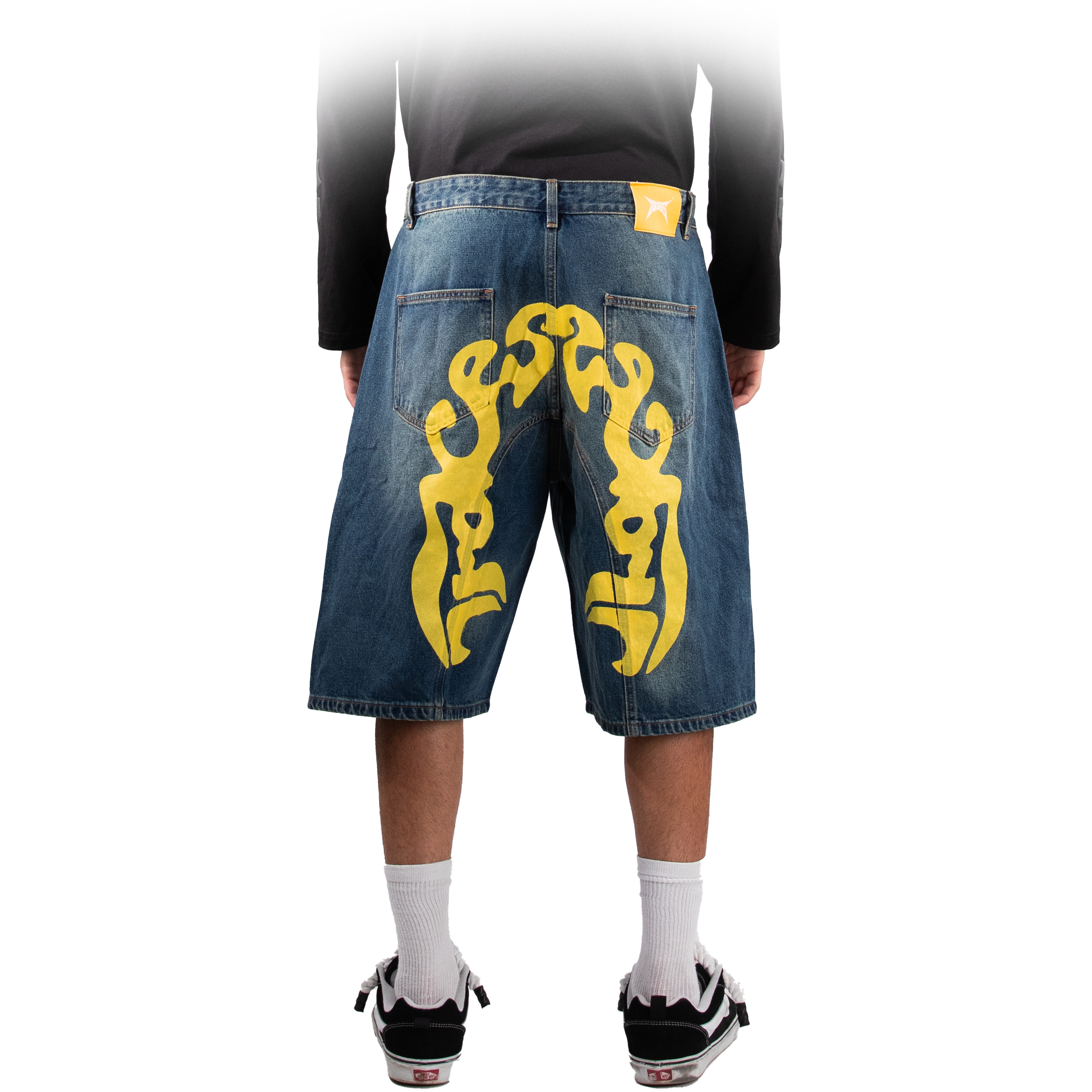 Back view of baggy denim shorts featuring large yellow FACES artwork across both legs and a yellow FACES logo patch on the waistband.